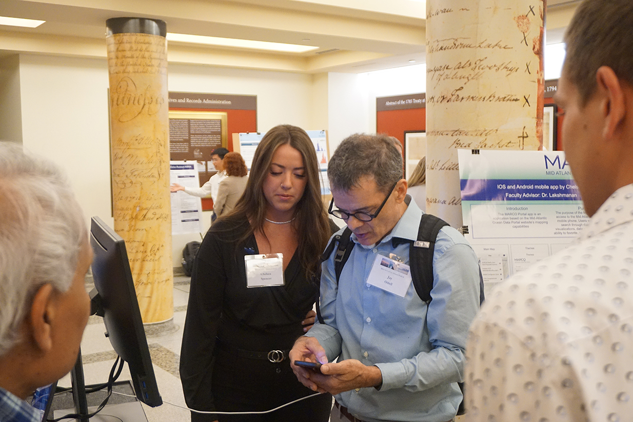 A student demonstrates a mobile app at poster session